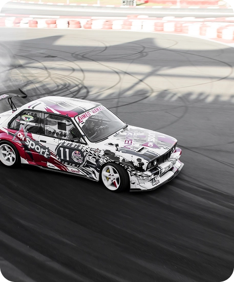Carro de drift a acelerar num circuito de motorizadas durante uma prova de condução competitiva.